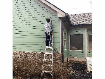 An individual on a ladder painting a home's exterior