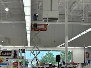 A man in a store is working on the ceiling,