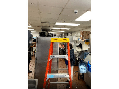 A ladder in a kitchen with a microwave and a refrigerator