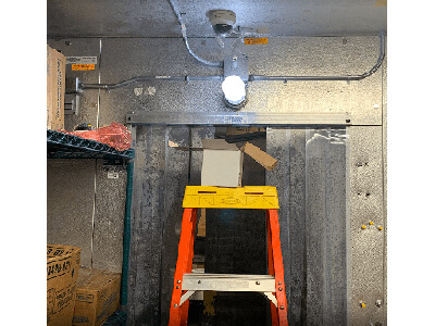 A ladder in the center of a room with a light hanging above it.