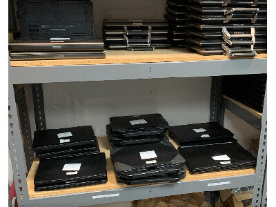 Several laptops neatly stacked on shelves in a room, ready for use
