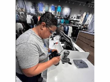 A woman focused on her computer screen, working diligently in a clothing store.